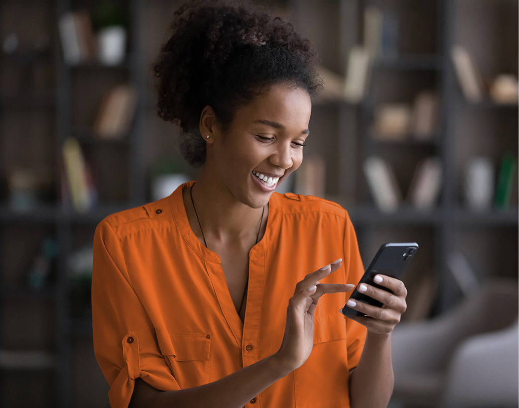 Mulher sorrindo usando app de conta corrente no celular para pagar boletos.