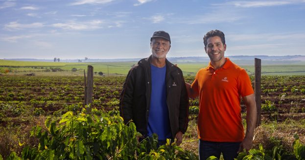 Dois produtores rurais lado a lado sorrindo no campo