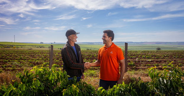 Dois produtores rurais apertando as mãos no campo