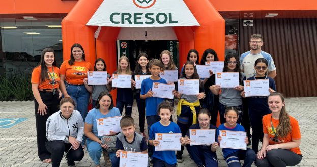 Alunos da Escola de Educação Básica Paulo Cristiano Heyse, no distrito de Moema, reunidos em frente à agência da Cresol Vale, com os certificados da formação dos projetos educacionais Poupe Poupe e Um Olhar para o Futuro.